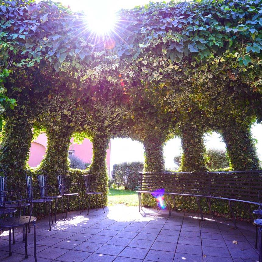 Galleria di archi verdi illuminati dal sole nel giardino di Villa Mirador